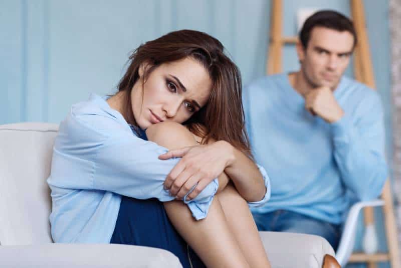 Joven disgustada sentada en casa junto a su marido