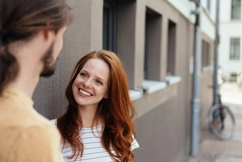 a red-haired smiling girl on the street talking to a man