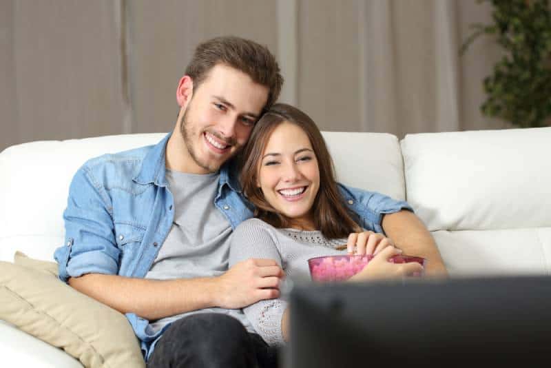 couple watching a movie on tv sitting on a couch at home