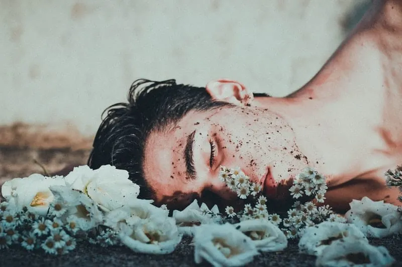 man laying on white flowers