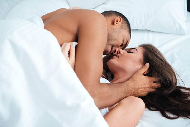 casal romântico deitado na cama debaixo de um cobertor