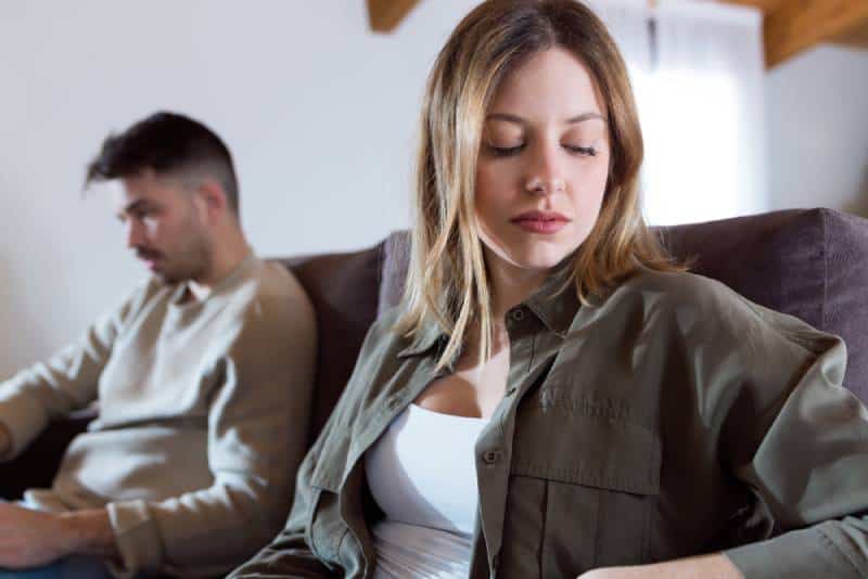 sad couple sitting on sofa at home