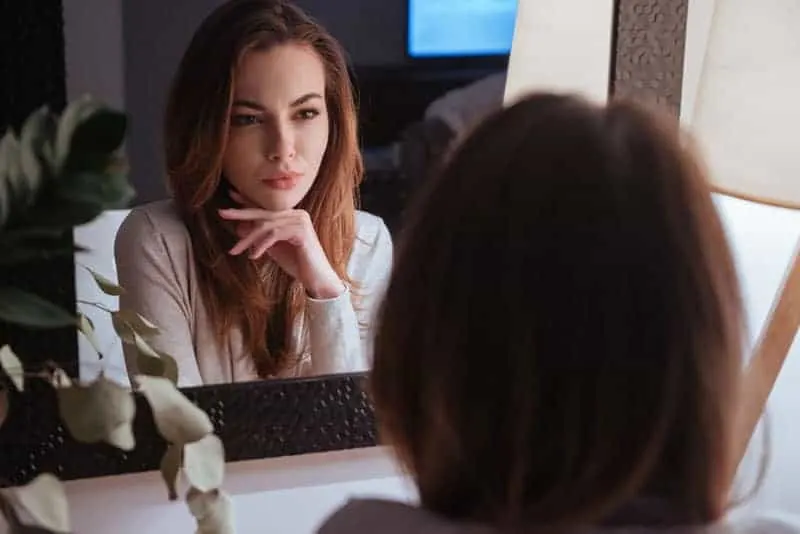serious woman looking at herself in the mirror