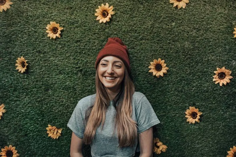 smiling woman leaning on flower wall