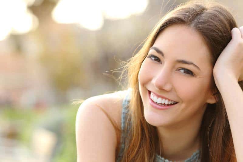 mujer sonriente apoyada en su mano al aire libre