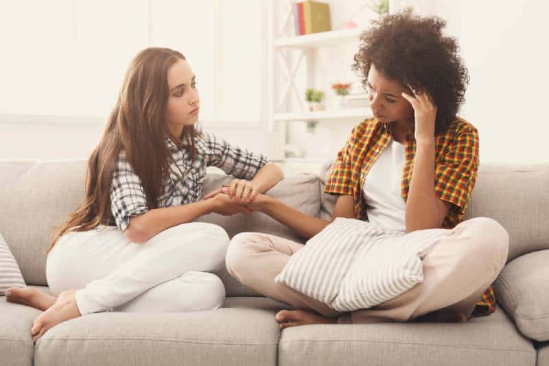 dos mujeres hablando de problemas sentadas en el sofá de su casa