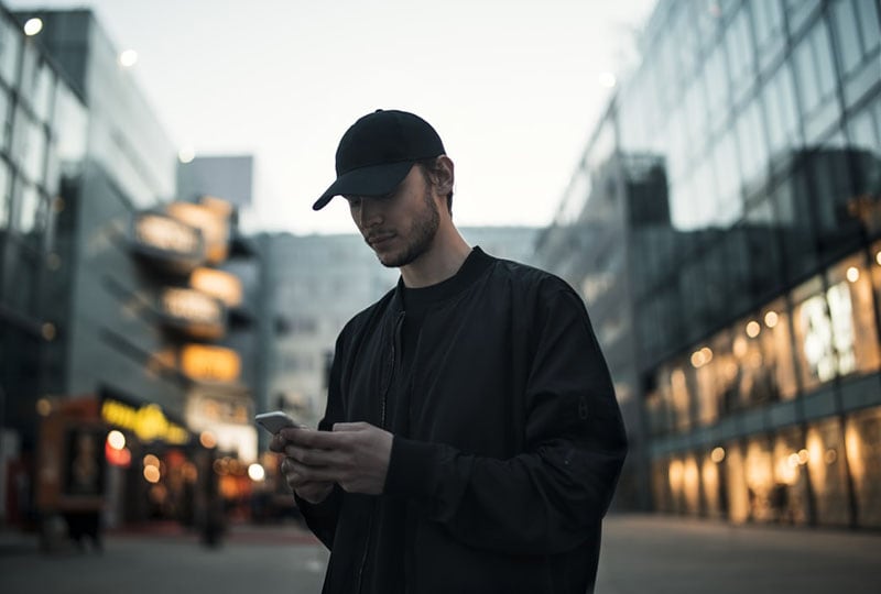 young man with hat texting