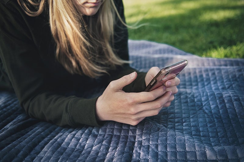 jovem mulher deitada e a enviar mensagens de texto