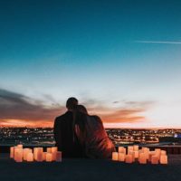 back view of couple surrounded by candles watching a city