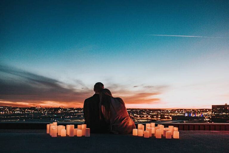 vista trasera de pareja rodeada de velas observando una ciudad