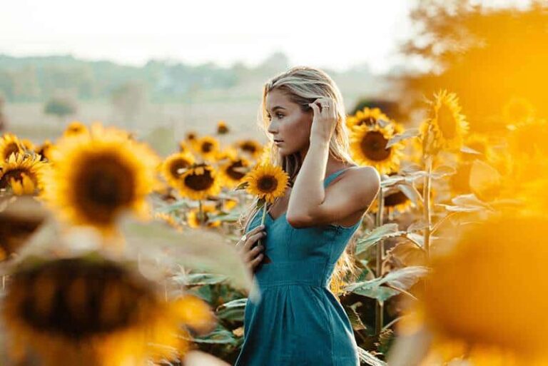 woman wearing blue dress surround with sunflowers