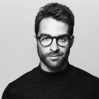 foto in bianco e nero di un uomo barbuto con occhiali da vista