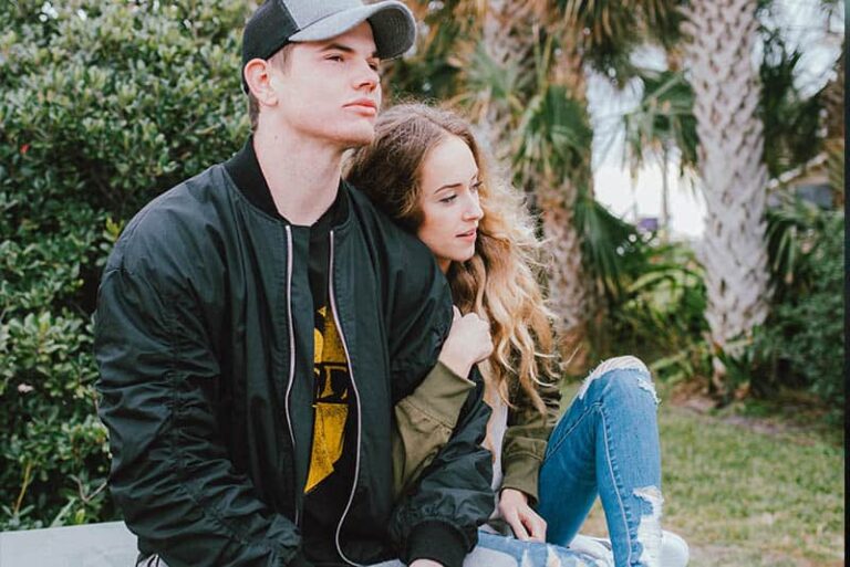 woman holds man arms while sitting outside