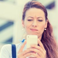 una mujer confusa lee algo en su móvil