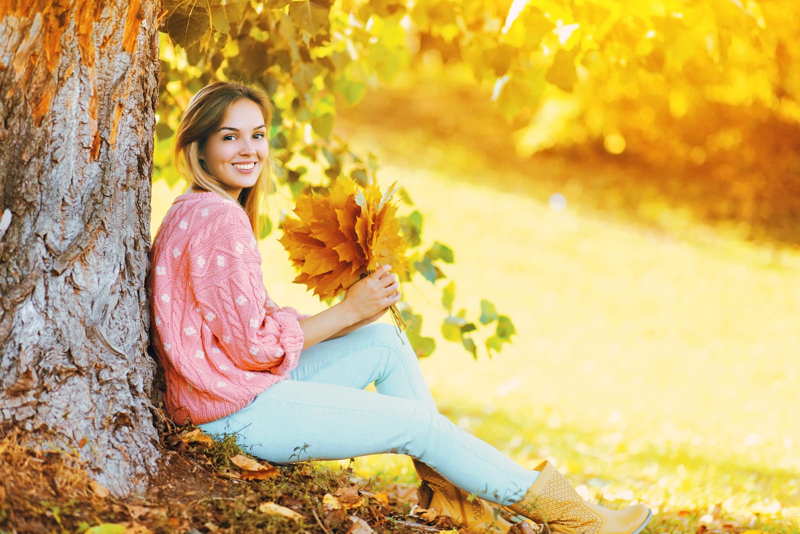 a woman sitting on the grass holding a leaf in her hand