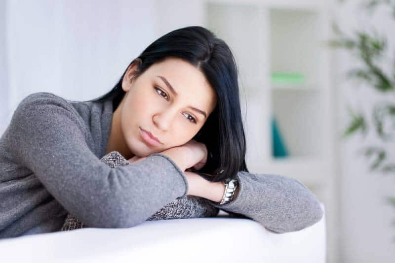 sad woman lying her head on sofa in living room