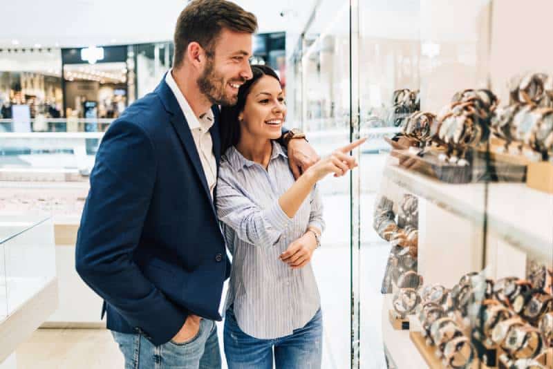  pareja sonriente frente a la joyería