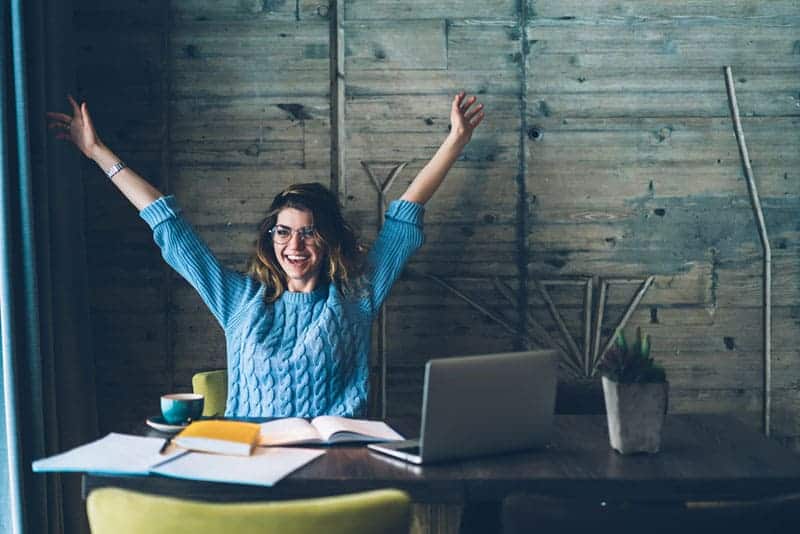 smiling woman raising hands in office