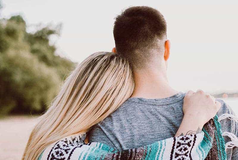 back view of woman hugging man over shoulder