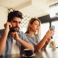 casal num café a utilizar os seus smartphones