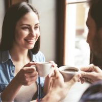 mulher sorridente a ouvir homem num encontro para café