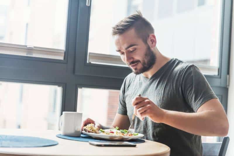 Un hombre tomando una comida sana por la mañana, desayunando en casa