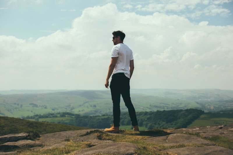 Man standing on boulders overlooking the hills and mountains