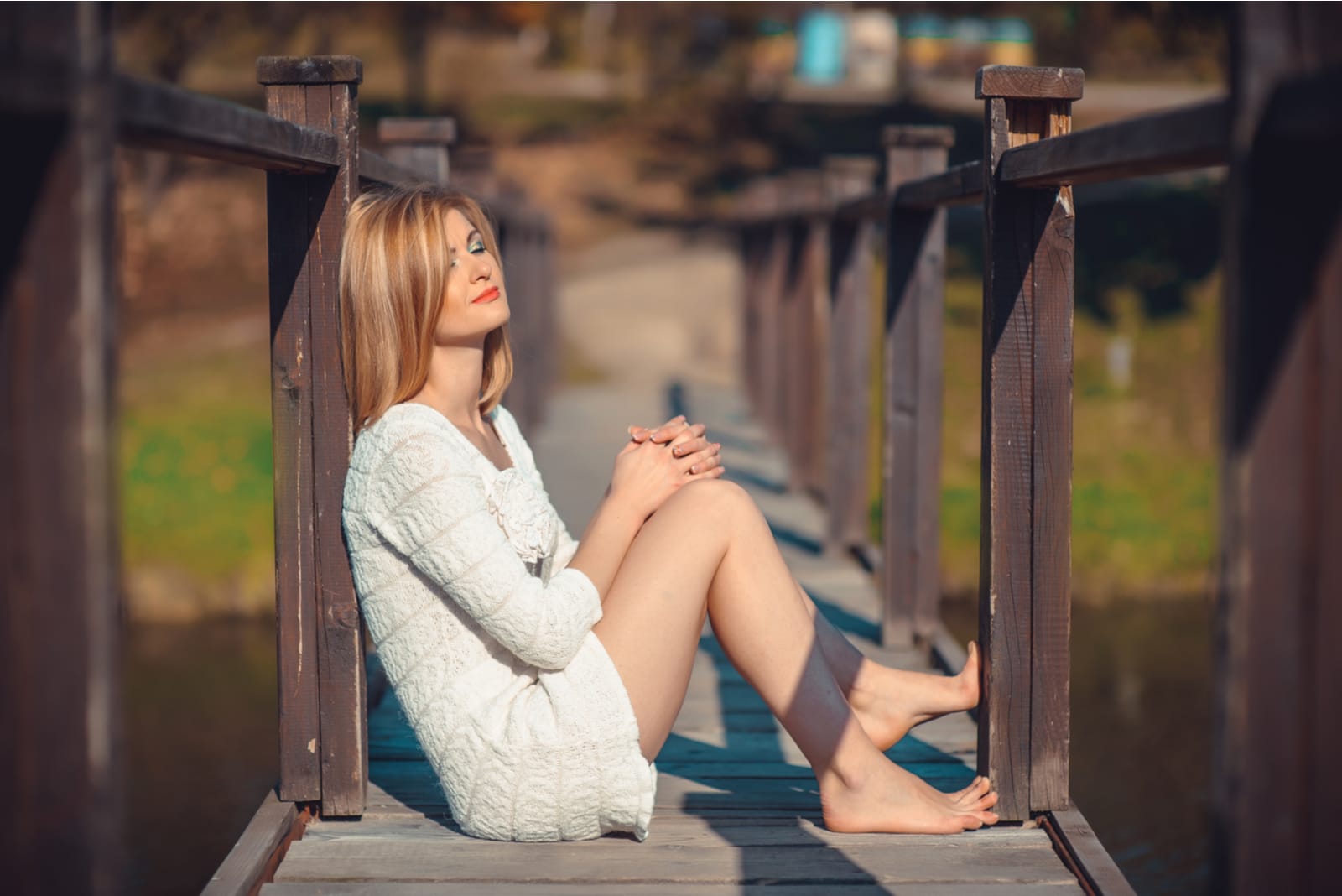uma loira atraente senta-se numa velha ponte de madeira