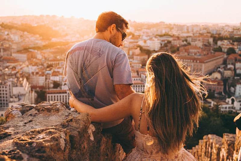 couple sitting on the hill and looking at city