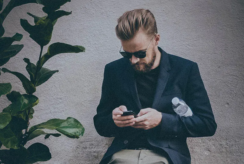 man in suit typing on his phone
