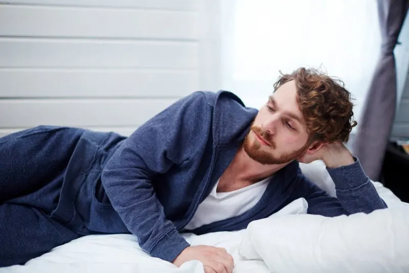 pensive man lying in bed