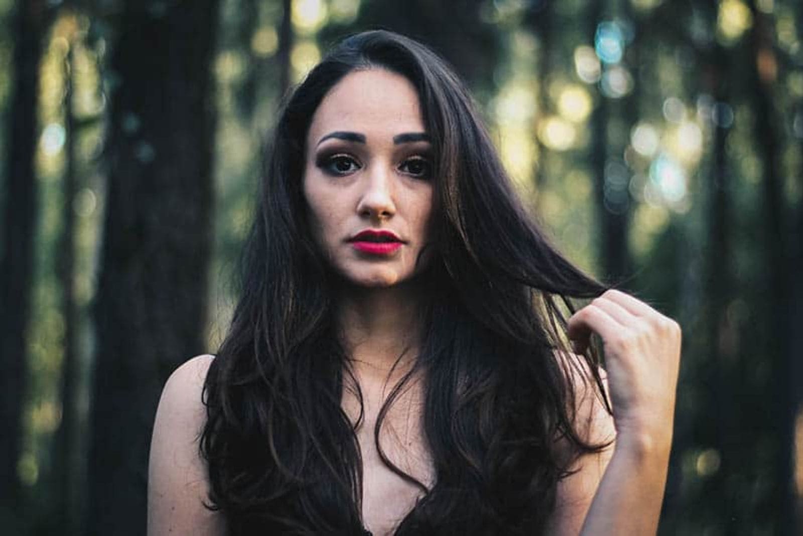 pensive woman in forest playing with her hair