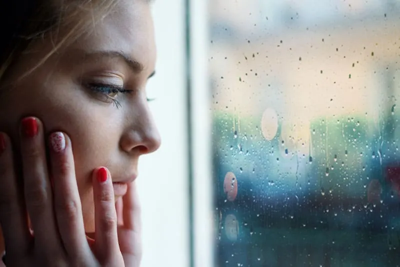 sad young woman looking through the window