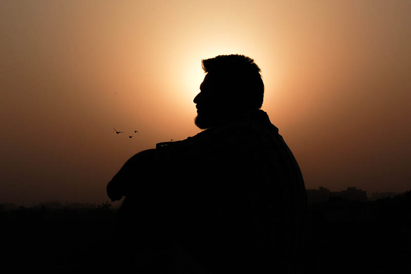 silhouette of man sitting outside