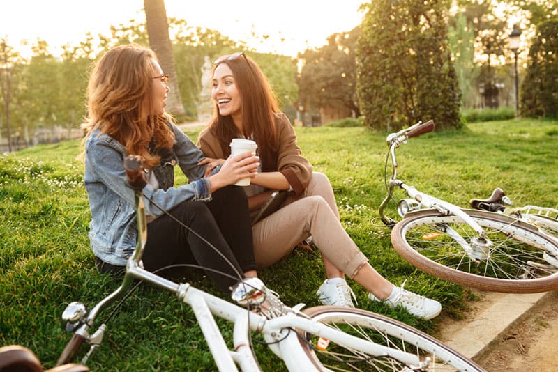 two female friends sitting on the grass and talking
