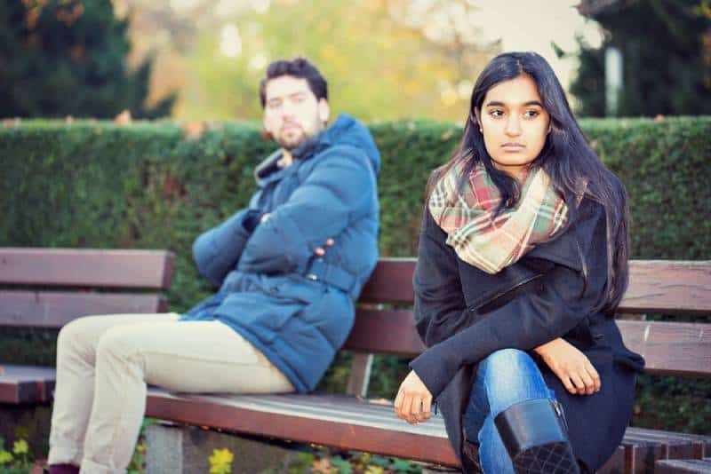upset couple sitting on a park bench