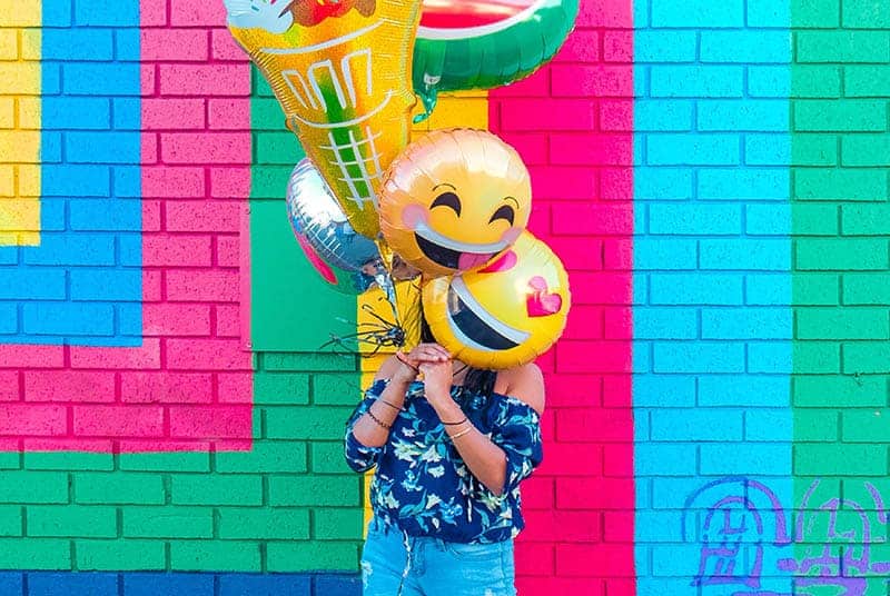 woman holding a emojis balloons