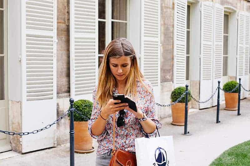 woman standing outside and typing on phone