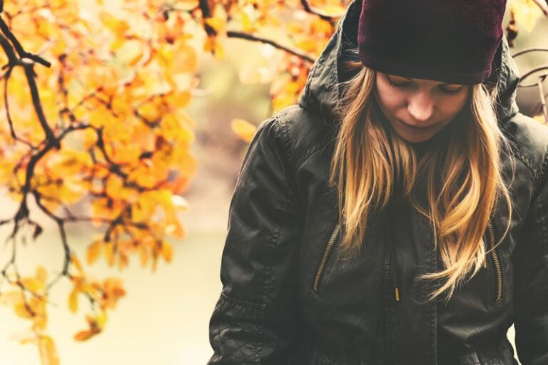 sad woman standing outdoor with hat on the head