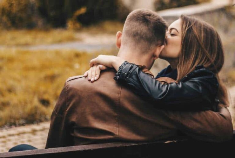 lovey woman kisses his man while hugging him