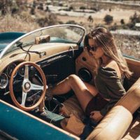 mulher jovem e bonita com óculos de sol e sentada num carro