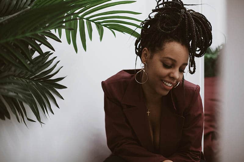 a smiling black woman in a brown jacket sits and smiles