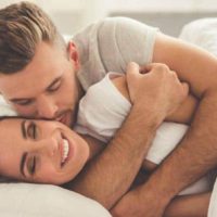 lovely man hugging and kissing girlfriend on bed