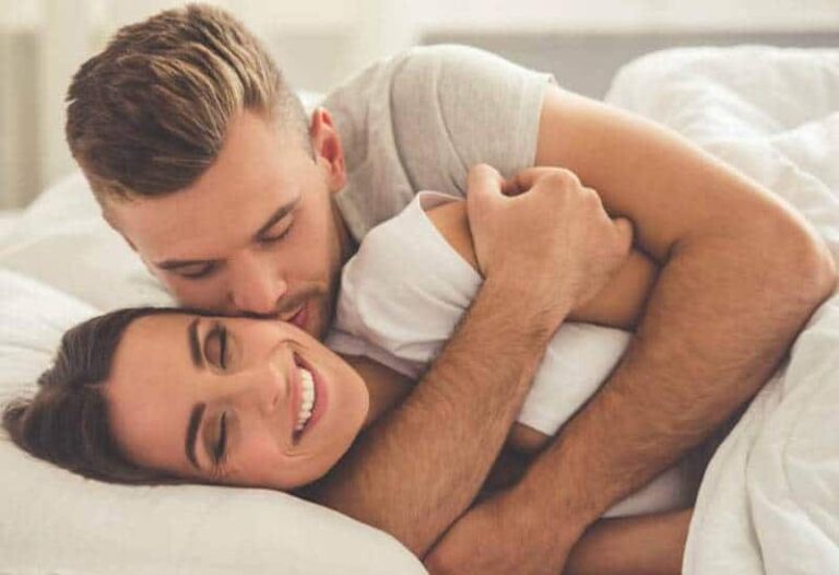 lovely man hugging and kissing girlfriend on bed