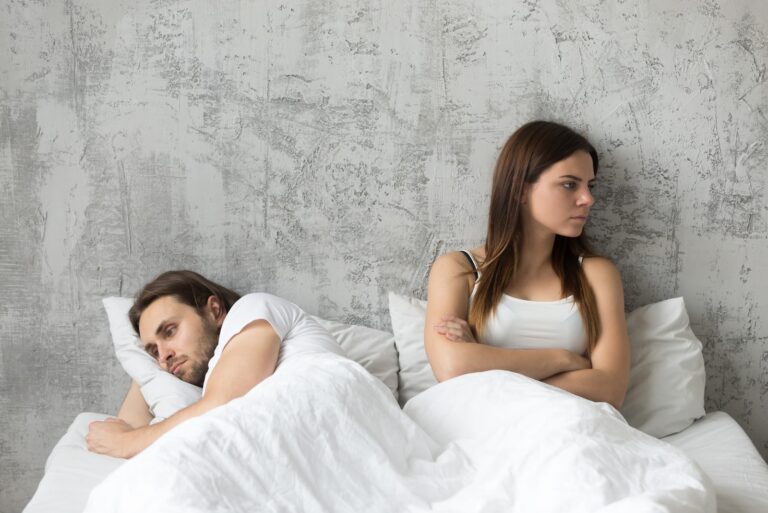 sad couple sitting in bed