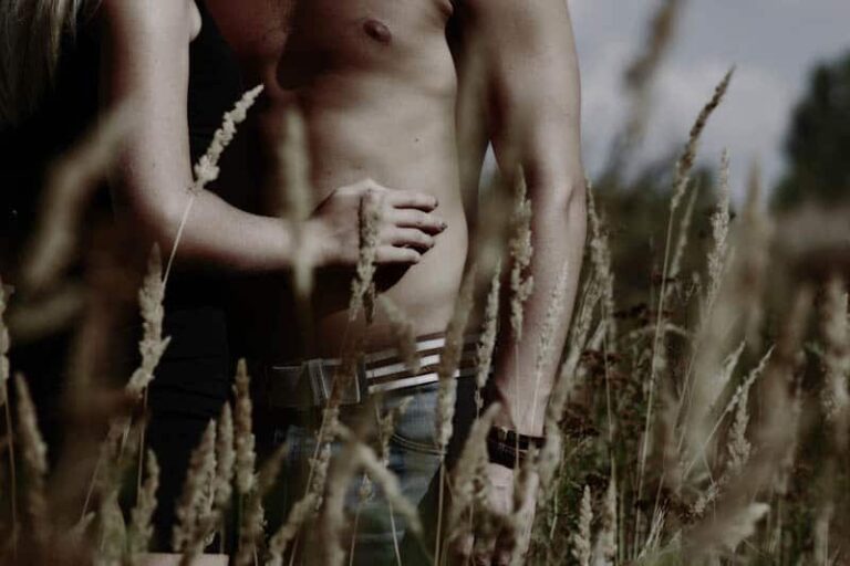 mujer toca a hombre en topless en campo de hierba