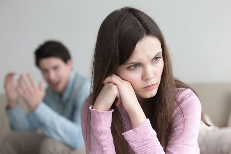 mujer triste sentada mientras un hombre grita