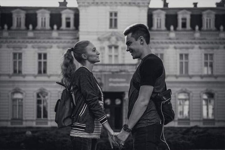 side view of smiling couple looking each other and holding hands