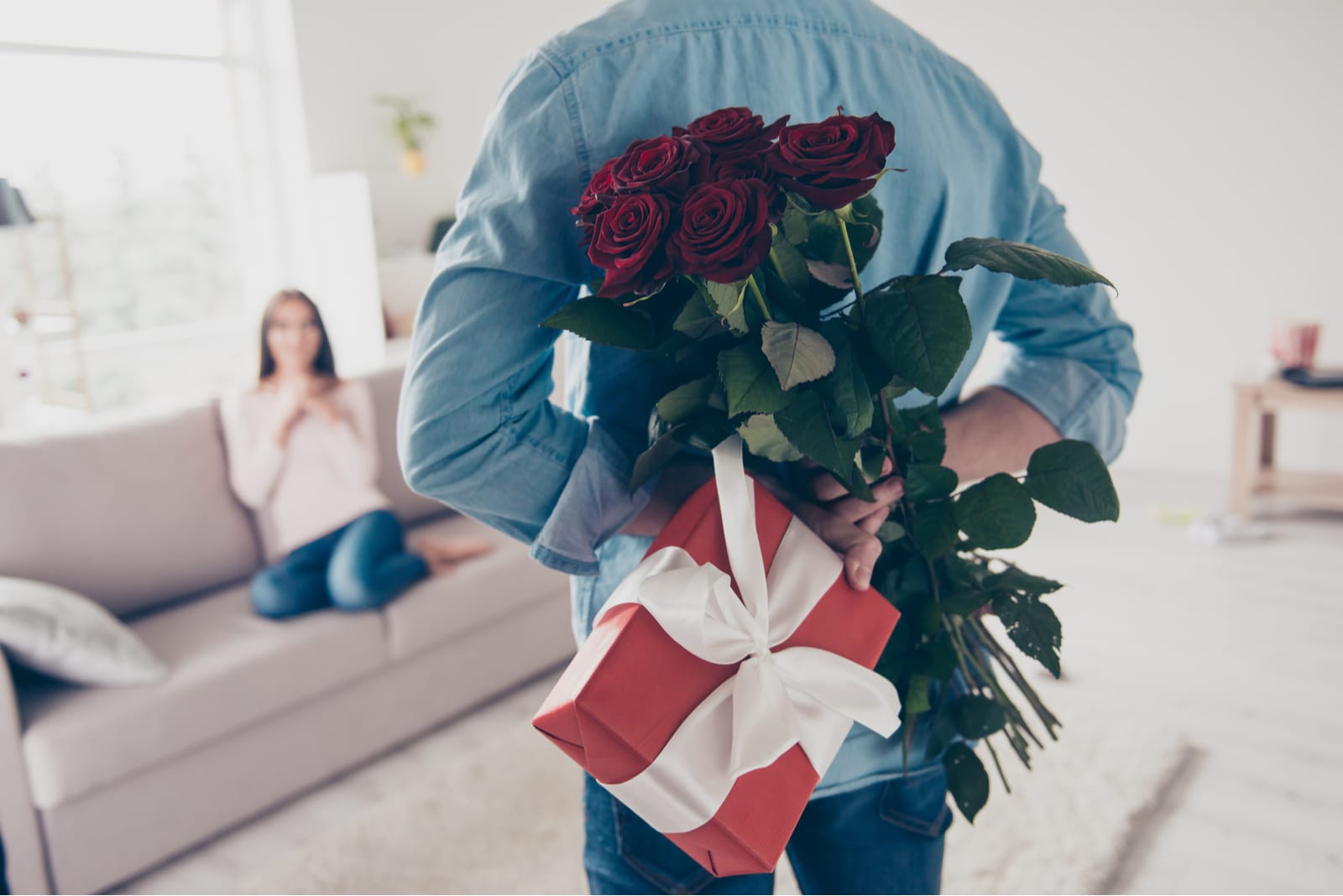 man surprising woman with flowers and gift