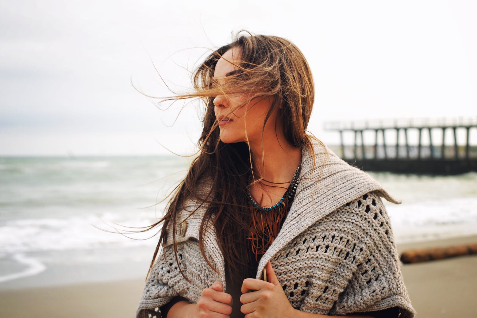 a woman with long brown hair stands on the beach